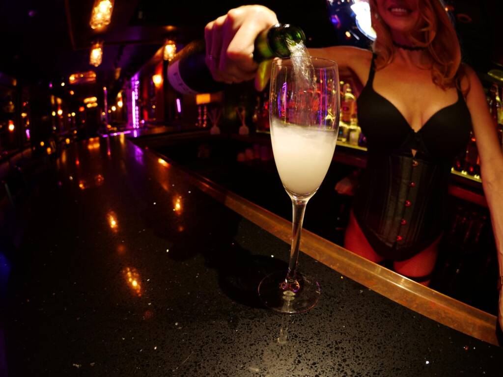 blonde bartender pouring glass of champagne at camelot showbar dc